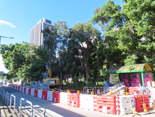 A road with a construction site and trees

AI-generated content may be incorrect.